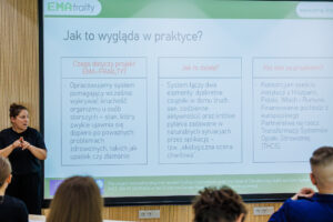Slajd prezentacji projektu EMA-FRAILTY pt. "Jak to wygląda w praktyce?" z opisem systemu wykrywania kruchości organizmu u osób starszych, obok tłumaczka języka migowego.