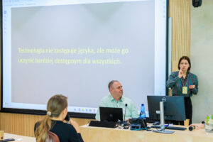 Slajd z cytatem "Technologia nie zastępuje języka, ale może go uczynić bardziej dostępnym dla wszystkich", Natalia Pacyga tłumaczy na język migowy obok mężczyzny w jasnozielonej koszuli.